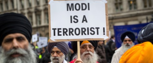 LONDON, ENGLAND - NOVEMBER 12: A protestor demonstrating against Indian Prime Minister Narendra Modi holds a placards outside Downing Street on November 12, 2015 in London, England. Modi began a three-day visit to the United Kingdom today which will be marked by a speech to Parliament a meeting with the Queen and an address to crowds at Wembley Stadium. (Photo by Rob Stothard/Getty Images)
